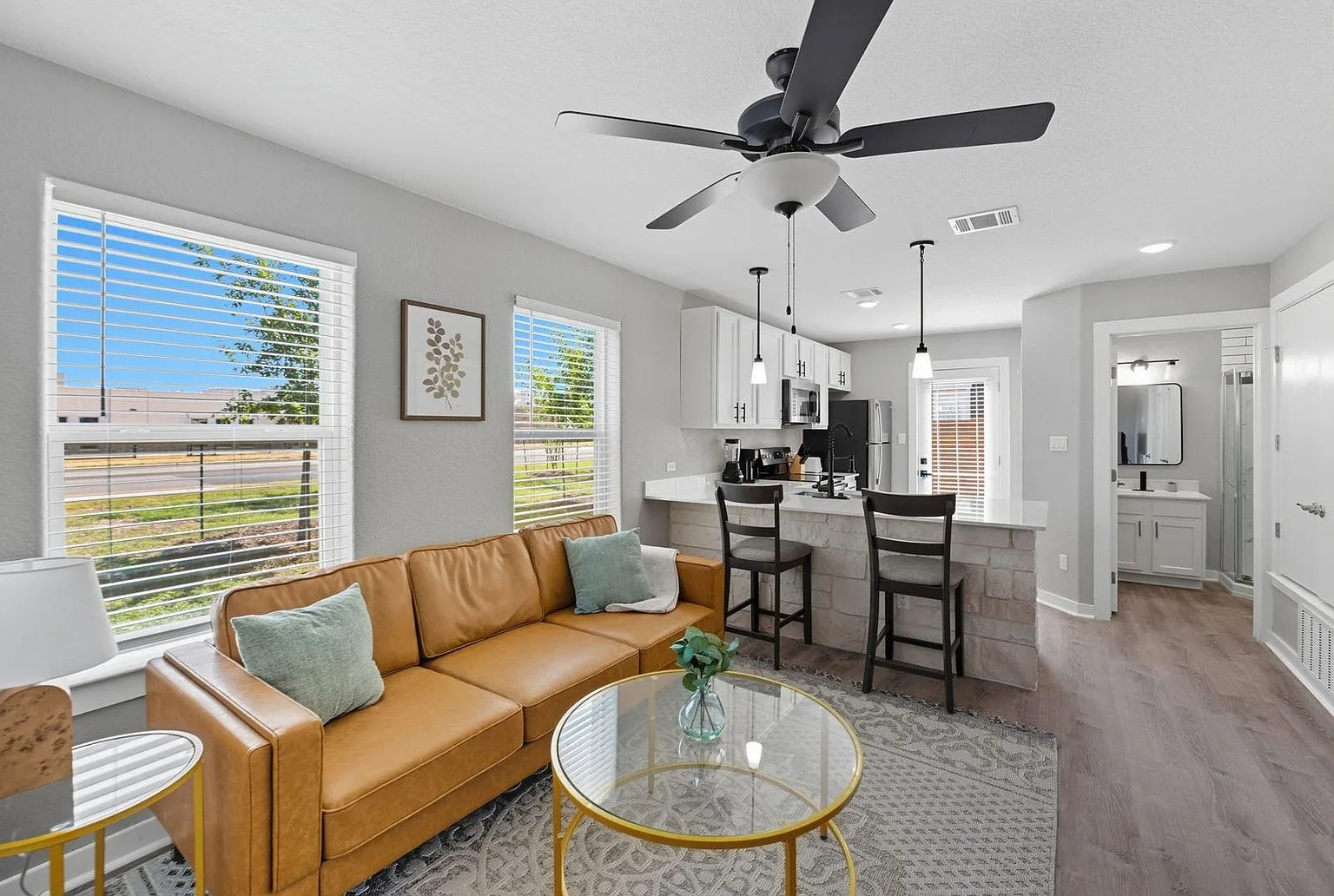 Furnished living room at 20 Tate Lane with a leather sofa, rug and a view through to the kitchen