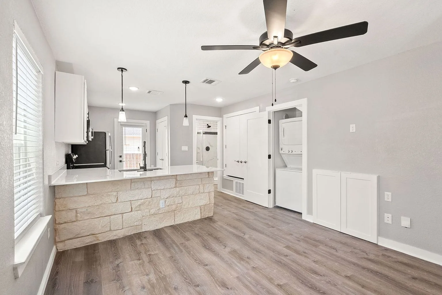 Open living and kitchen with a stone island, quartz counters and a stacked washer and dryer