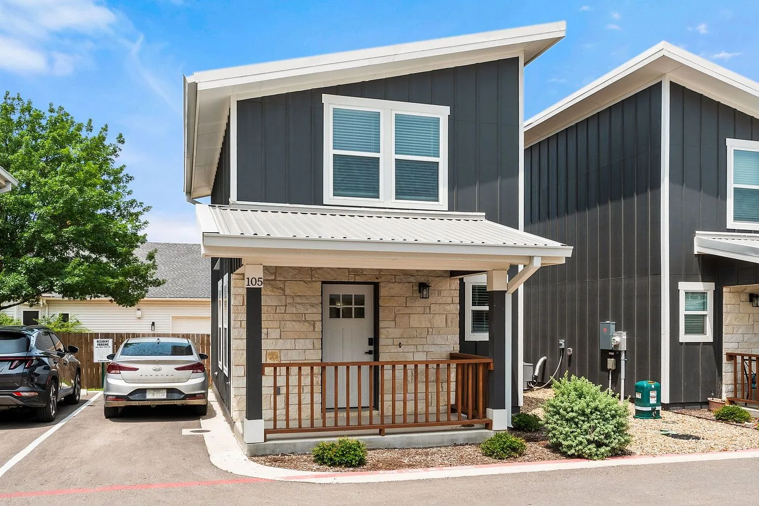 A detached two-storey home at 20 Tate Lane with a stone porch, cedar rail and its own driveway