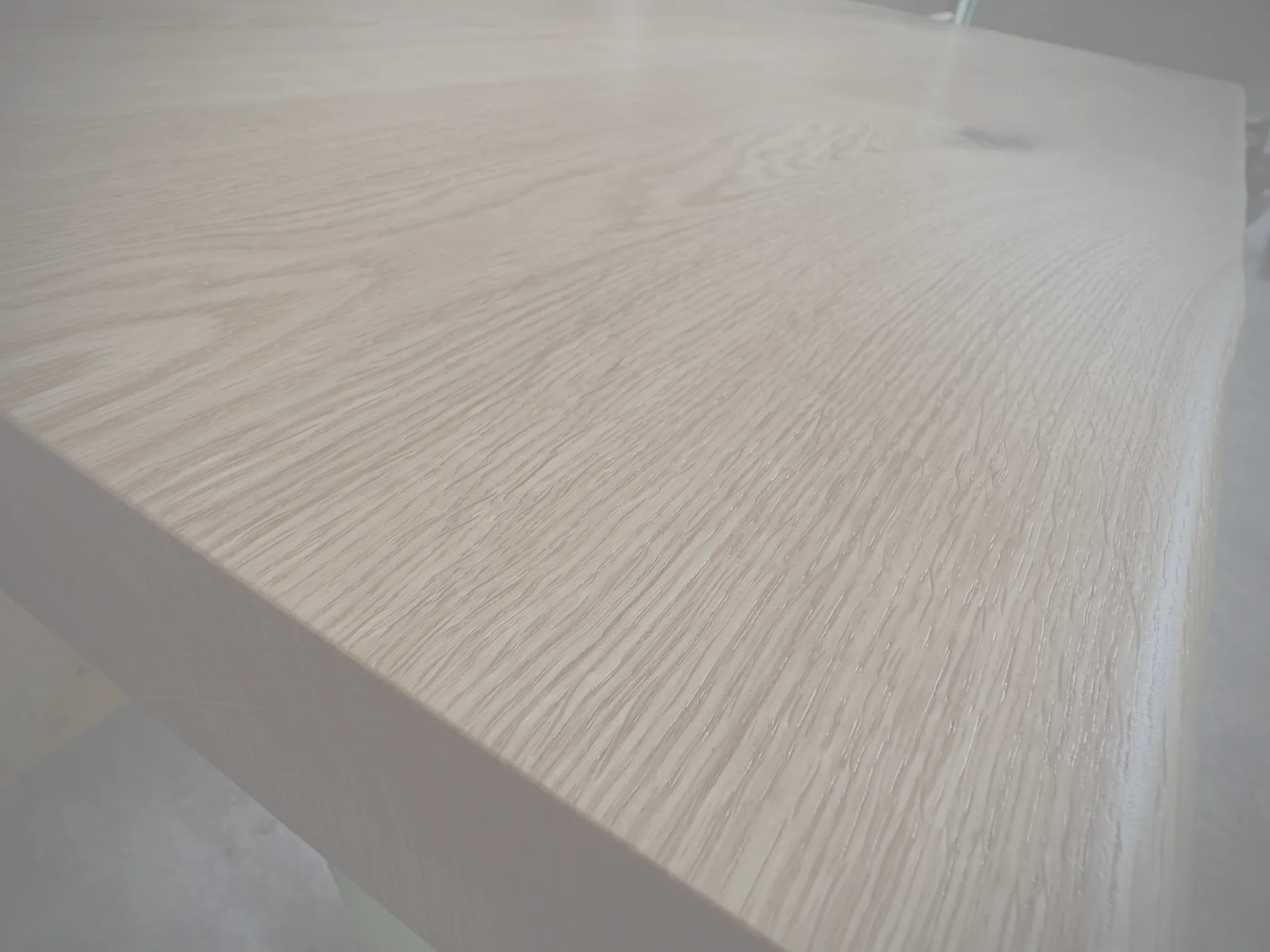 A live-edge oak table top in close up, the grain running across the frame