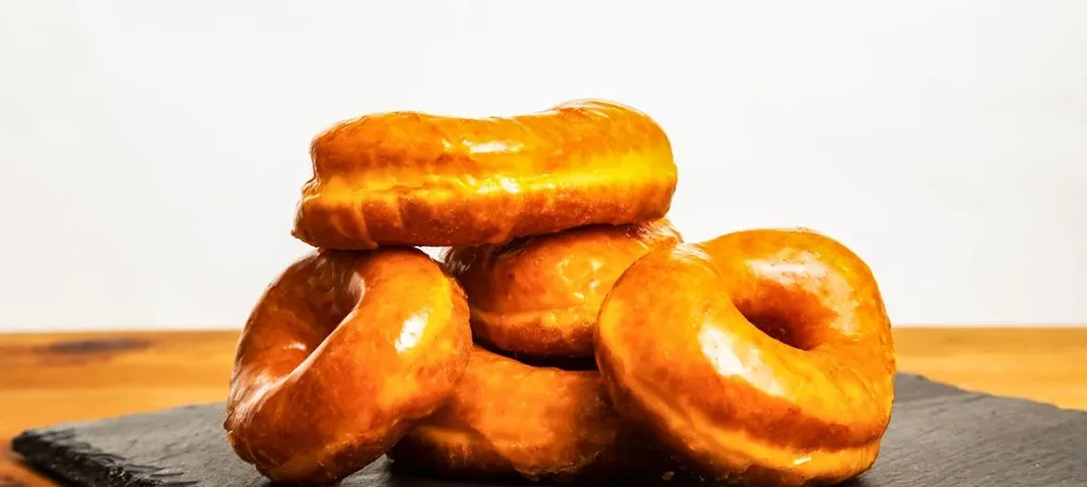 A stack of glazed doughnuts from Round Rock Donuts on a slate board