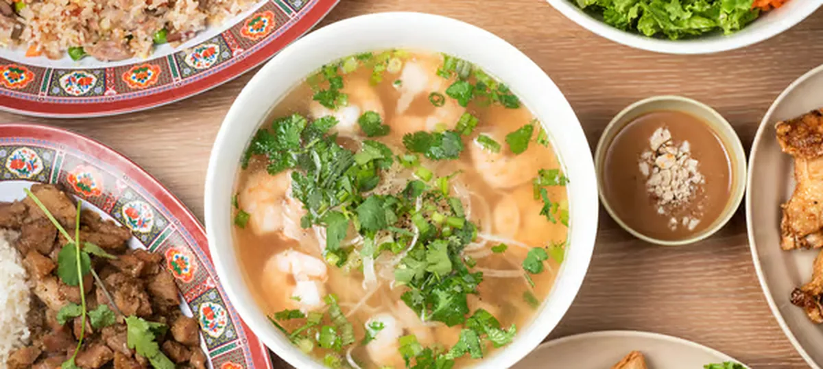 A bowl of phở with herbs and side dishes at Noble Phở, Round Rock