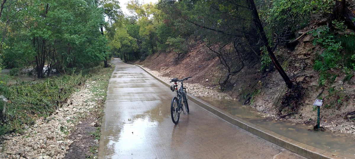 The concrete Brushy Creek Regional Trail running beside the creek, with a bicycle parked on it