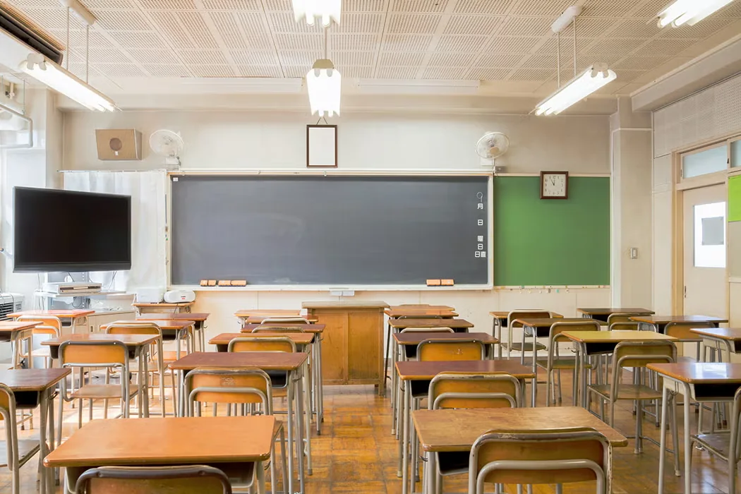 A classroom with a blackboard and rows of wooden desks